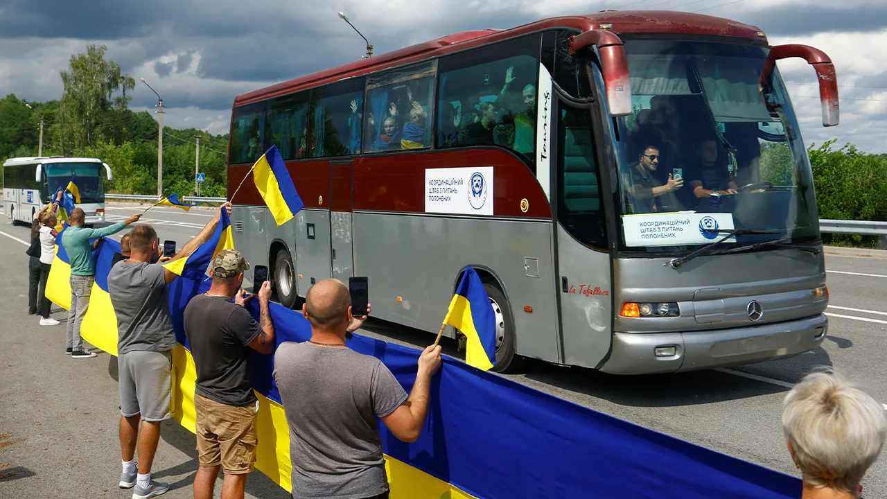 Residents wave national flags while they meet Ukrainian prisoners of war (POWs) after a swap, amid Russia's attack on Ukraine, at an undisclosed location in Ukraine August 19, 2026. REUTERS/Valentyn Ogirenko