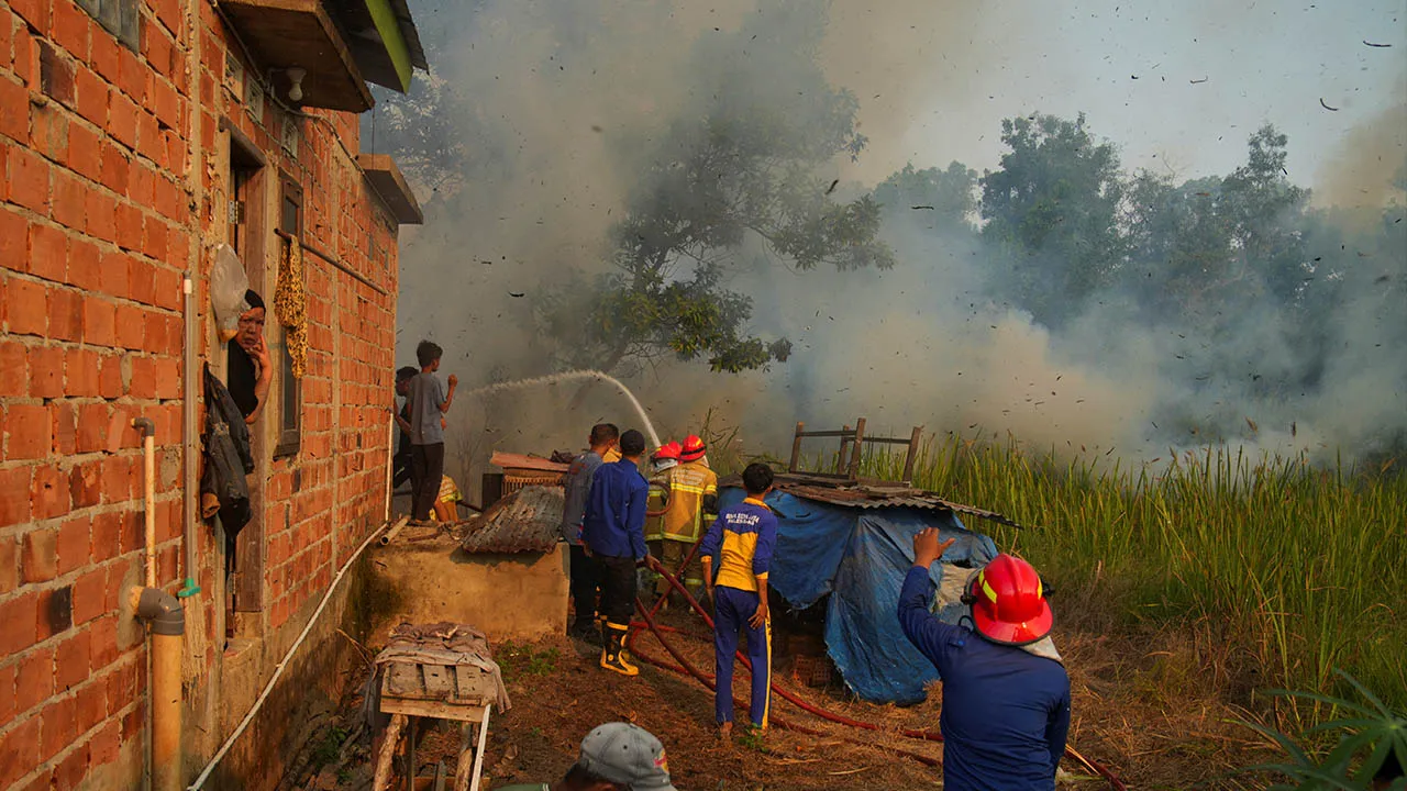 Firefighters attempt to extinguish a wildfire, spread near a residential area in Palembang, South Sumatra province, Indonesia, August 10, 2026. REUTERS/Abriansyah Liberto