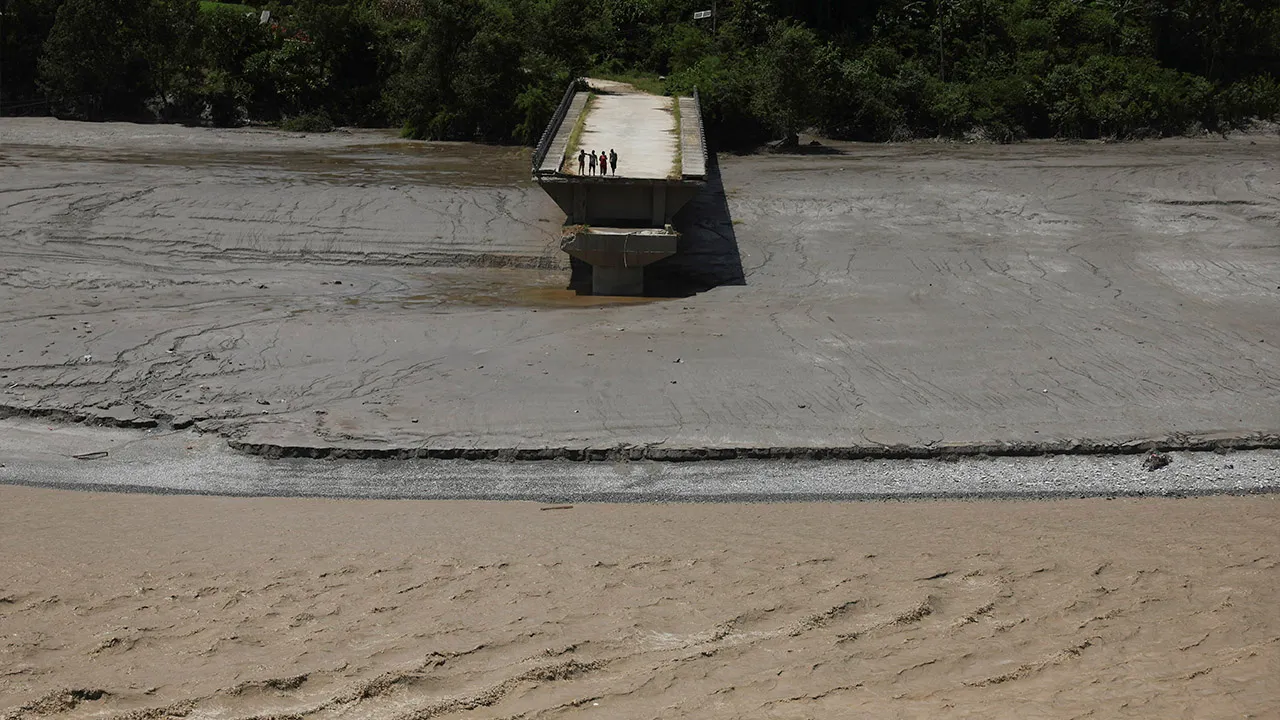 People stand on the edge of a broken bridge following a flash flood in Galchhi, Nepal, August 27, 2026. REUTERS/Francis Mascarenhas