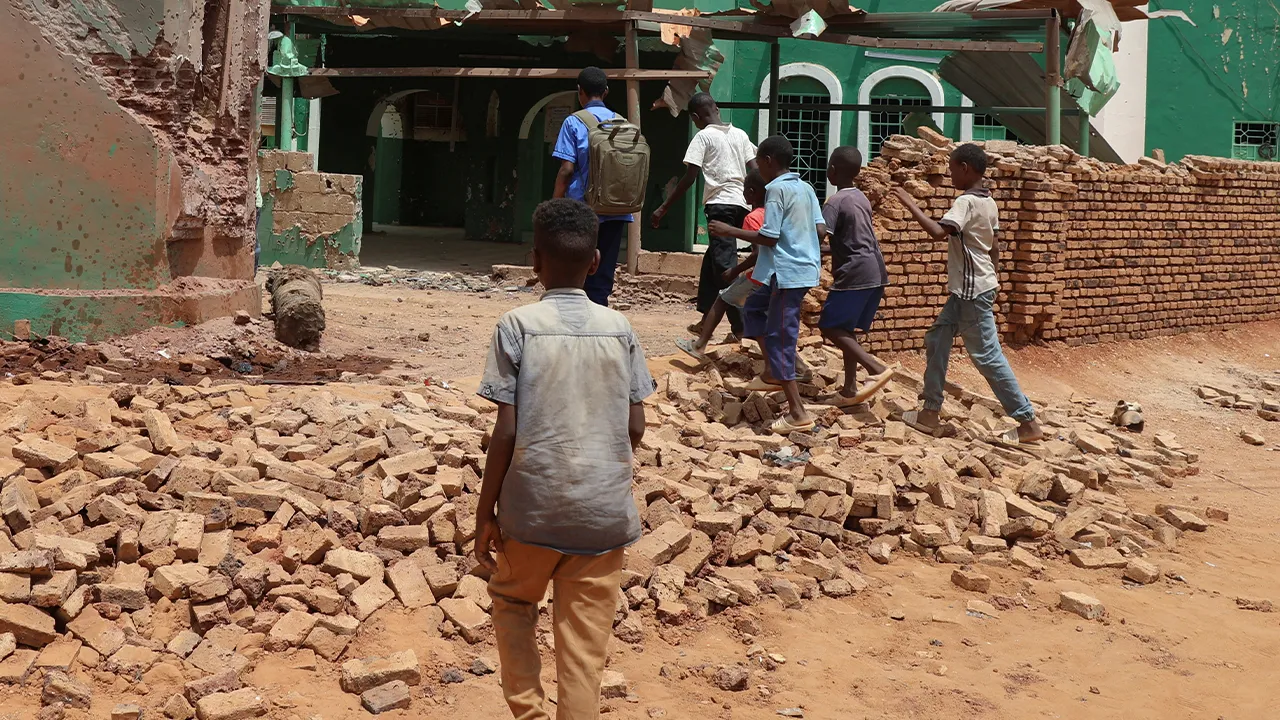 Children walk next to a collapsed mosque wall following a drone strike, in Khartoum North, in Bahri city, Sudan, August 12, 2026. REUTERS/El Tayeb Siddig