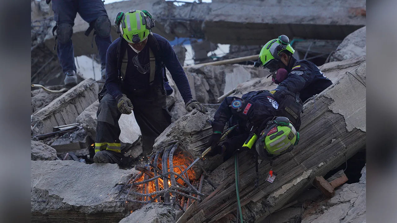Rescue workers cut through debris as they search for survivors the day after an earthquake struck Cali, Colombia, Tuesday, Aug. 11, 2026. (AP Photo/Ivan Valencia)