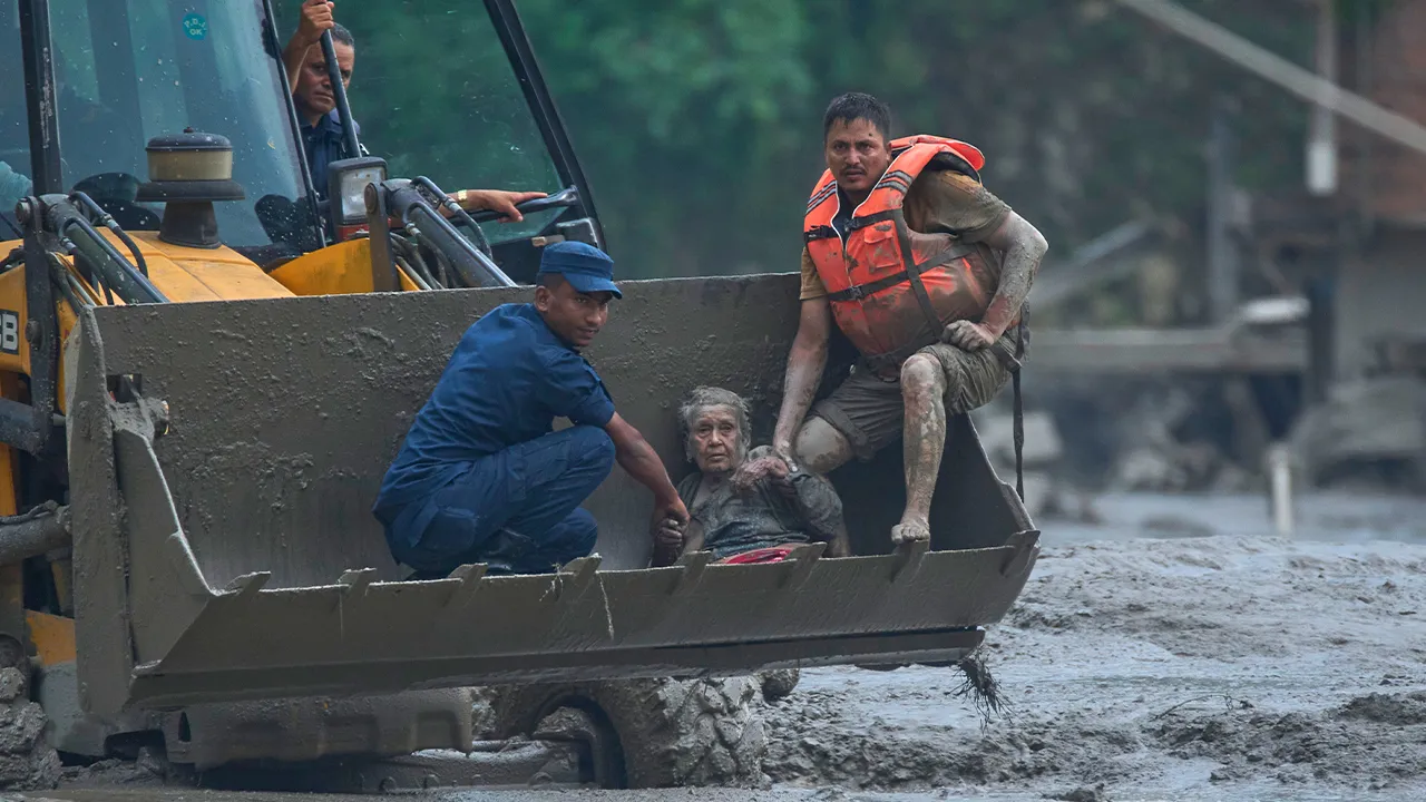 Rescuers use an earthmover to carry a victim of flash flooding to safety along the Trishuli River in Nepal's Nuwakot district, Wednesday, Aug. 26, 2026. (AP Photo/Niranjan Shrestha)