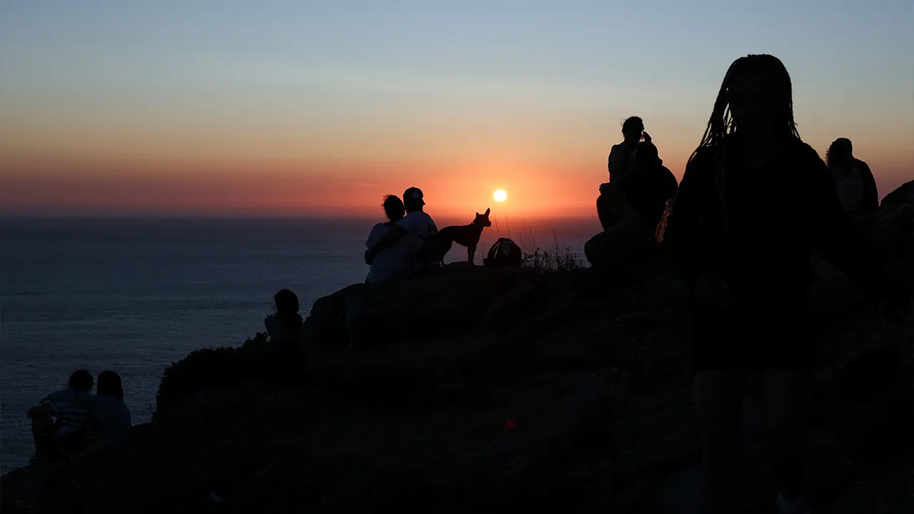 Tourists look at the sunset the day before the solar eclipse, on the Costa da Morte ("Coast of Death"), once considered the end of the world and a traditional destination for pilgrims completing the Camino de Santiago, in northwestern Spain, August 11, 2026. REUTERS/Nacho Doce