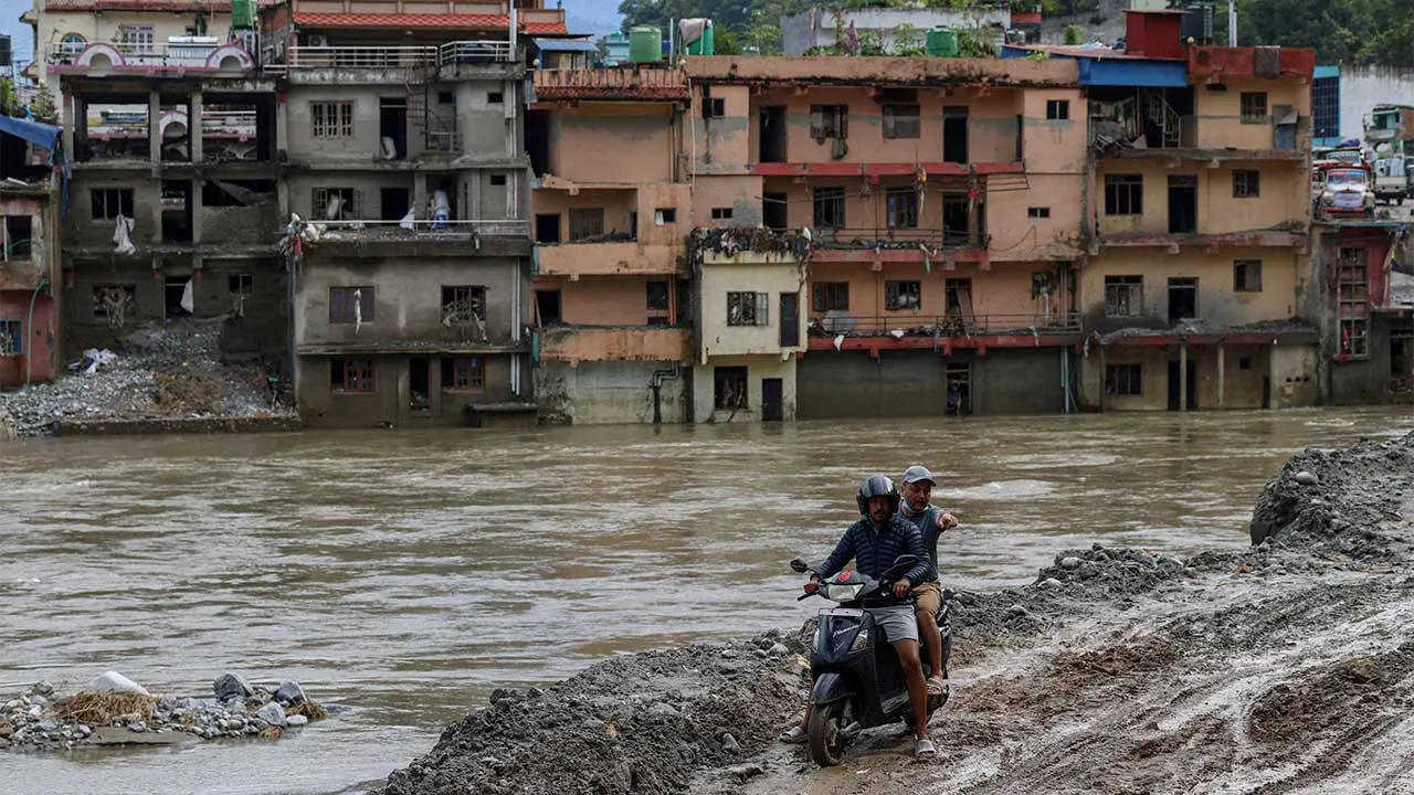 FILE PHOTO: A motorcyclist rides through thick mud with flood-damaged houses in the background following deadly flash floods and a mudslide, in Devighat, Nuwakot district, Nepal, September 11, 2026. REUTERS/Tyrone Siu/File Photo