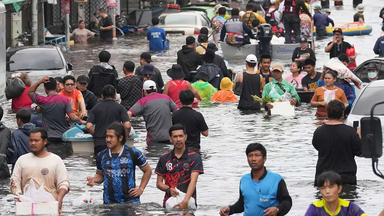 People wade through a flooded street after heavy rain in Bangkok, Thailand, Monday, Sept. 28, 2026. (AP Photo/Sakchai Lalit)