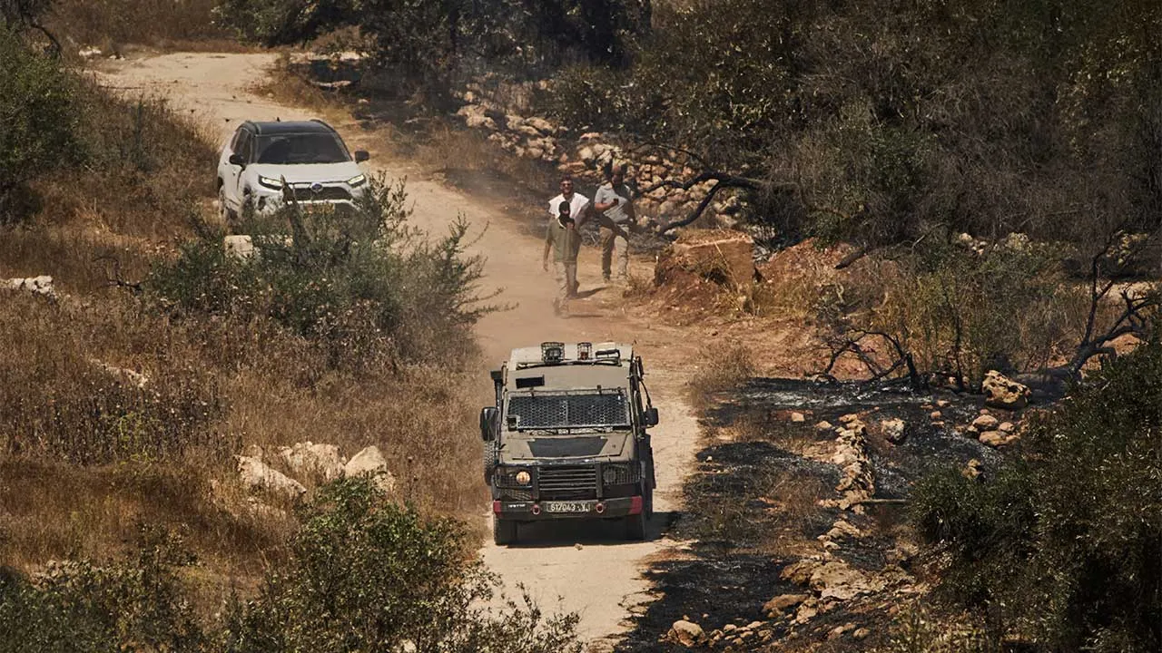 An Israeli army vehicle is seen next to Israeli settlers as they block access for local Palestinians in the West Bank village of Burqa, Thursday, Sept. 17, 2026, following an attack by settlers who, according to residents, set fire to the area. (AP Photo/Leo Correa)