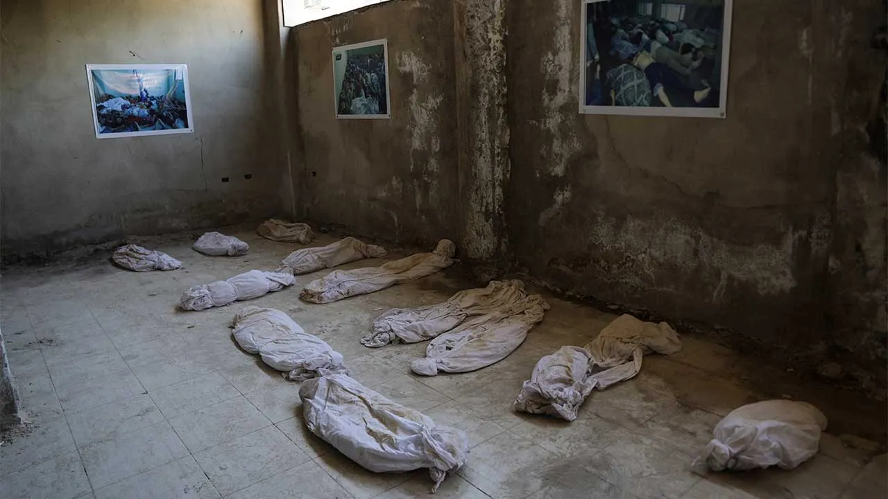 A group of symbolic shrouds representing victims of the chemical attack on the area in 2013 is displayed inside the room at Kafr Batna Hospital where the bodies of victims were placed after the massacre, in Eastern Ghouta, Syria, August 18, 2026. Original photographs documenting the massacre are displayed on the walls of the room. The exhibition is part of a museum documenting the reality experienced by residents and medical workers during the conflict. REUTERS/Khalil Ashawi