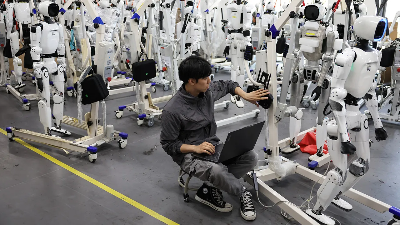 An engineer works among Tiangong Omni humanoid robots in the research and testing area of the Beijing Humanoid Robot Innovation Center, also known as X-Humanoid, in Beijing, China, September 4, 2026. REUTERS/Tingshu Wang