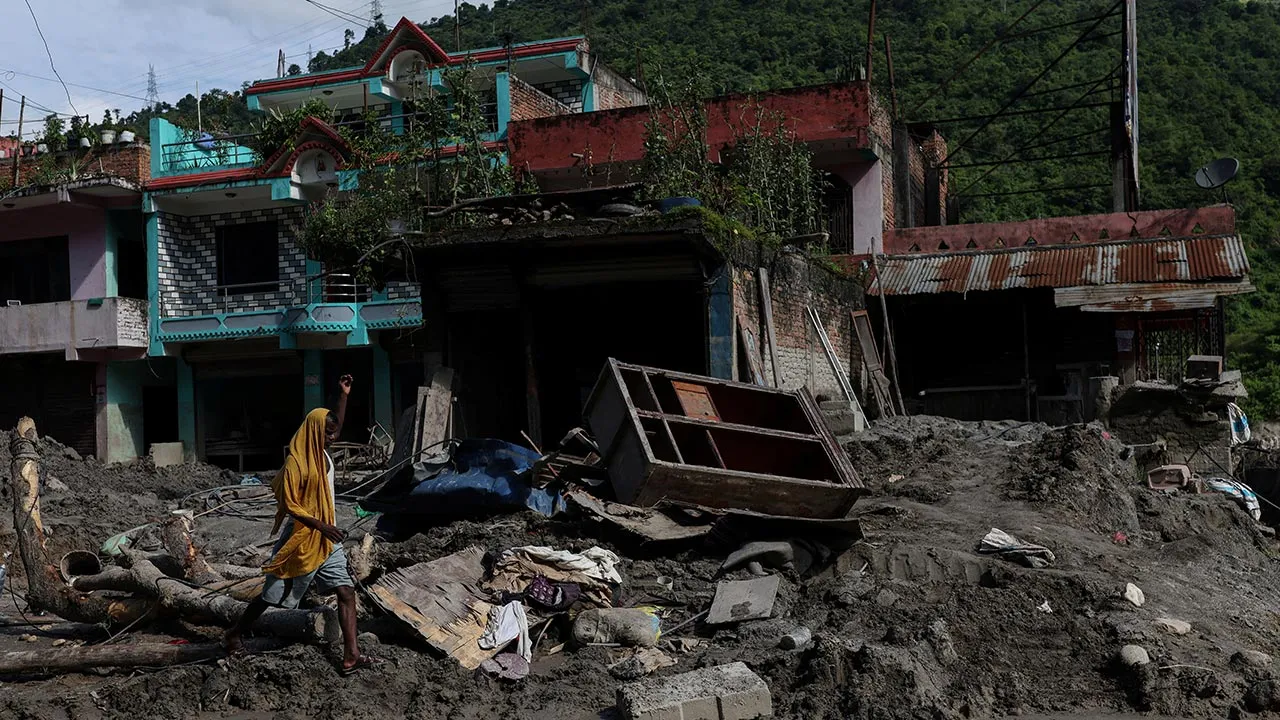 A man struggles to walk along a mud-covered road near his damaged house following deadly flash floods and a mudslide, in Dhading district, Nepal, September 14, 2026. REUTERS/Tyrone Siu
