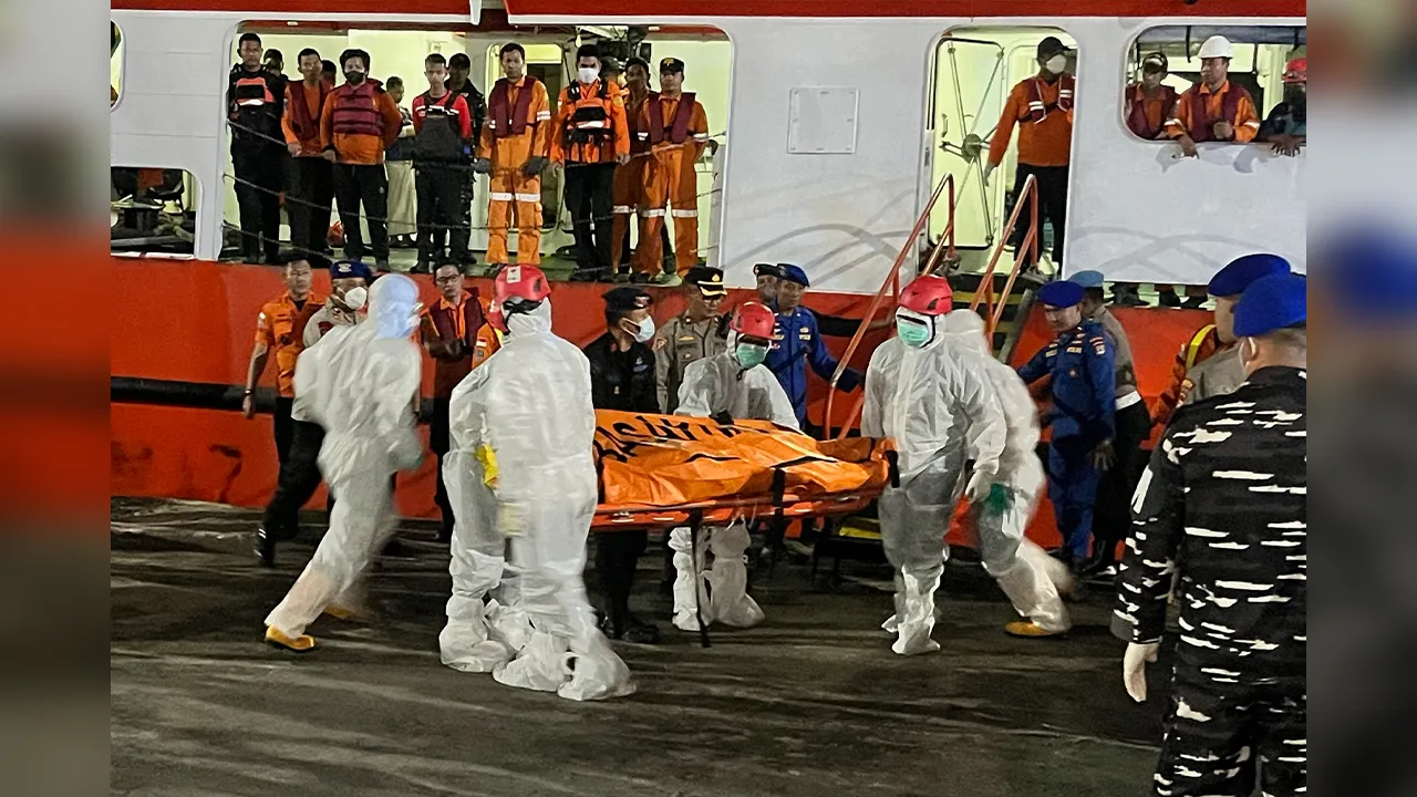 In this photo taken with a smartphone, rescuers carry the body of a victim from a passenger ferry that overturned in bad weather in the Java Sea upon arrival at a port in Banjarmasin, South Kalimantan, Indonesia, Friday, Sept. 18, 2026. (AP Photo/Iman Satria)