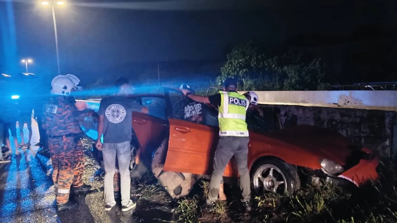 Anggota bomba dan polis membantu mengeluarkan pemandu kereta yang tersepit selepas melanggar pembahagi jalan di Slim River. Foto JBPM Perak.