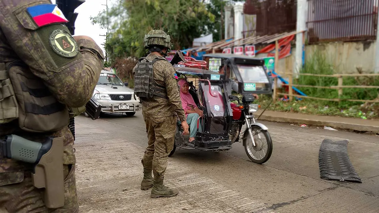 In this photo taken with a smartphone, Army soldiers check the flow of vehical traffic along the highway in Marantao town, Lanao del Sur province, southern Philippines on Sunday Sept 13, 2026. (AP Photo/ Froilan Gallardo)
