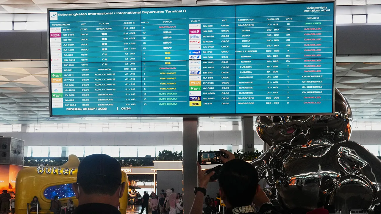 Travelers walk past an information board showing disrupted flights at Soekarno-Hatta International Airport in Tangerang, Indonesia, Sunday, Sept. 6, 2026. (AP Photo/Tatan Syuflana)
