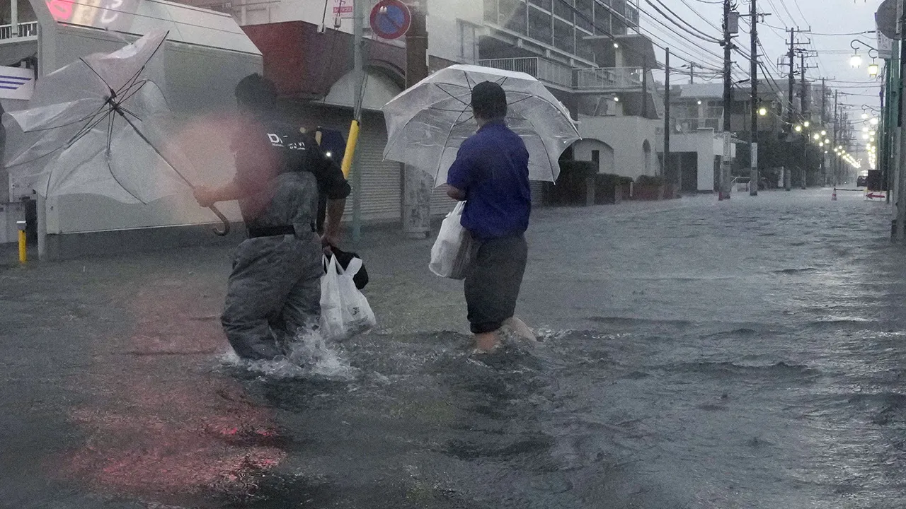 People wade through a flooded street as Typhoon Dujuan brings heavy rain, in Ichikawa, Chiba Prefecture, Japan, September 21, 2026 in this photo taken by Kyodo. Kyodo/via REUTERS 