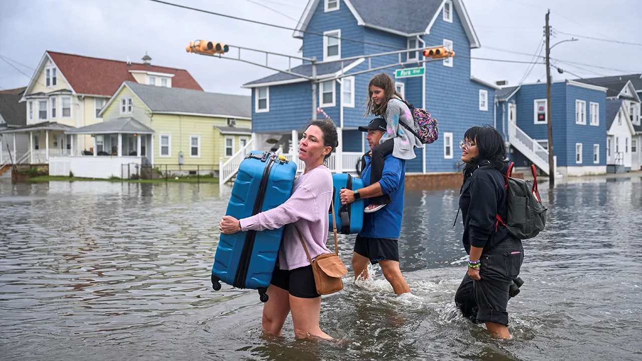 A family carrying personal belongings walk on a flooded street after heavy rain from a nor'easter fell as a strong coastal storm batters the U.S. northeast coast, in Wildwood, New Jersey, U.S., September 26, 2026. REUTERS/Vincent Alban