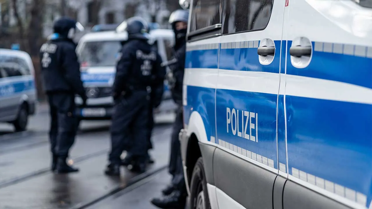 German police car from berlin is in the focus and in the blurry background are several riot police cops standing on the street and waiting for action on a demonstration. See Less