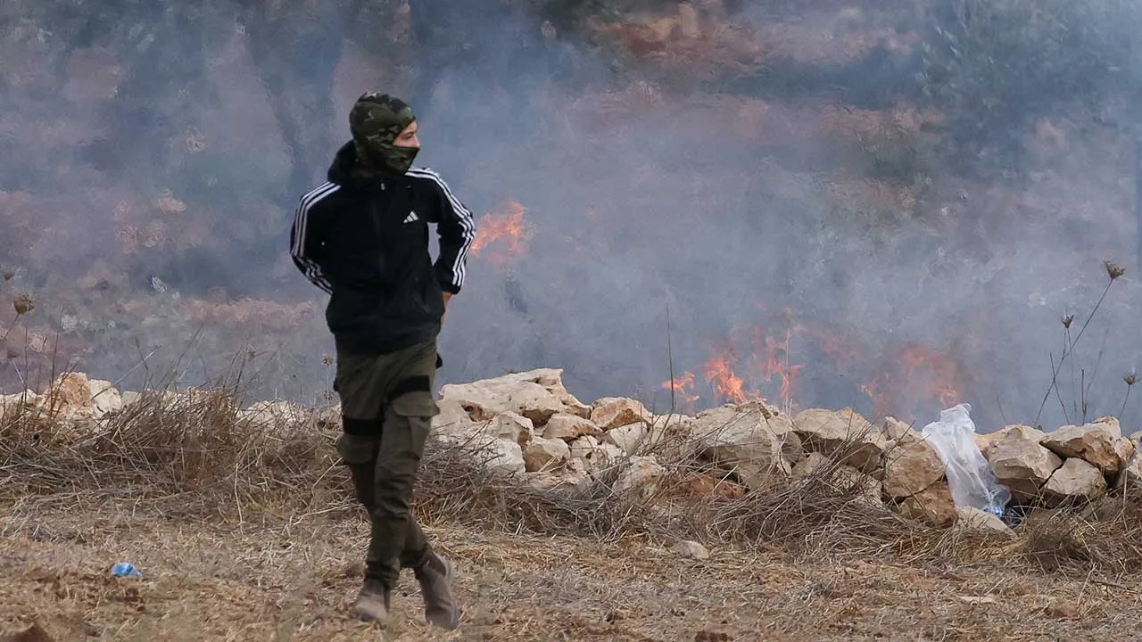 A Palestinian walks next to smoke and flames amid clashes with Israeli settlers during olive harvest in Abu Falah near Ramallah in the Israeli-occupied West Bank, October 16, 2026. REUTERS/Ammar Awad
