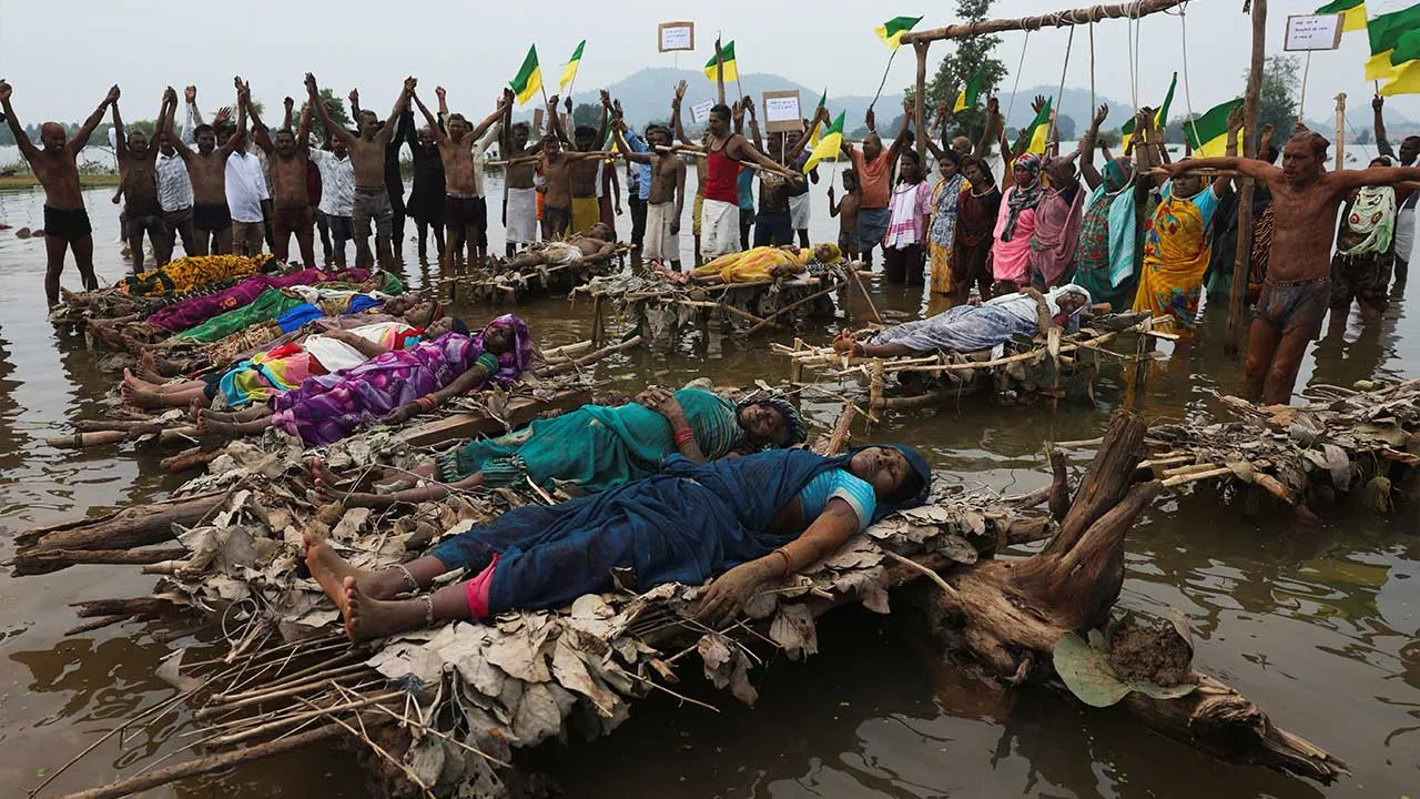 Protesters and members of families affected by the Ken-Betwa River Link Project lie on symbolic funeral pyres placed in the water, while others stand beneath a wooden frame with symbolic nooses around their necks during a protest near the Majhgawan Dam on the Ken River in Ajaygarh, Madhya Pradesh, India, September 20, 2026. REUTERS/Amit Dave