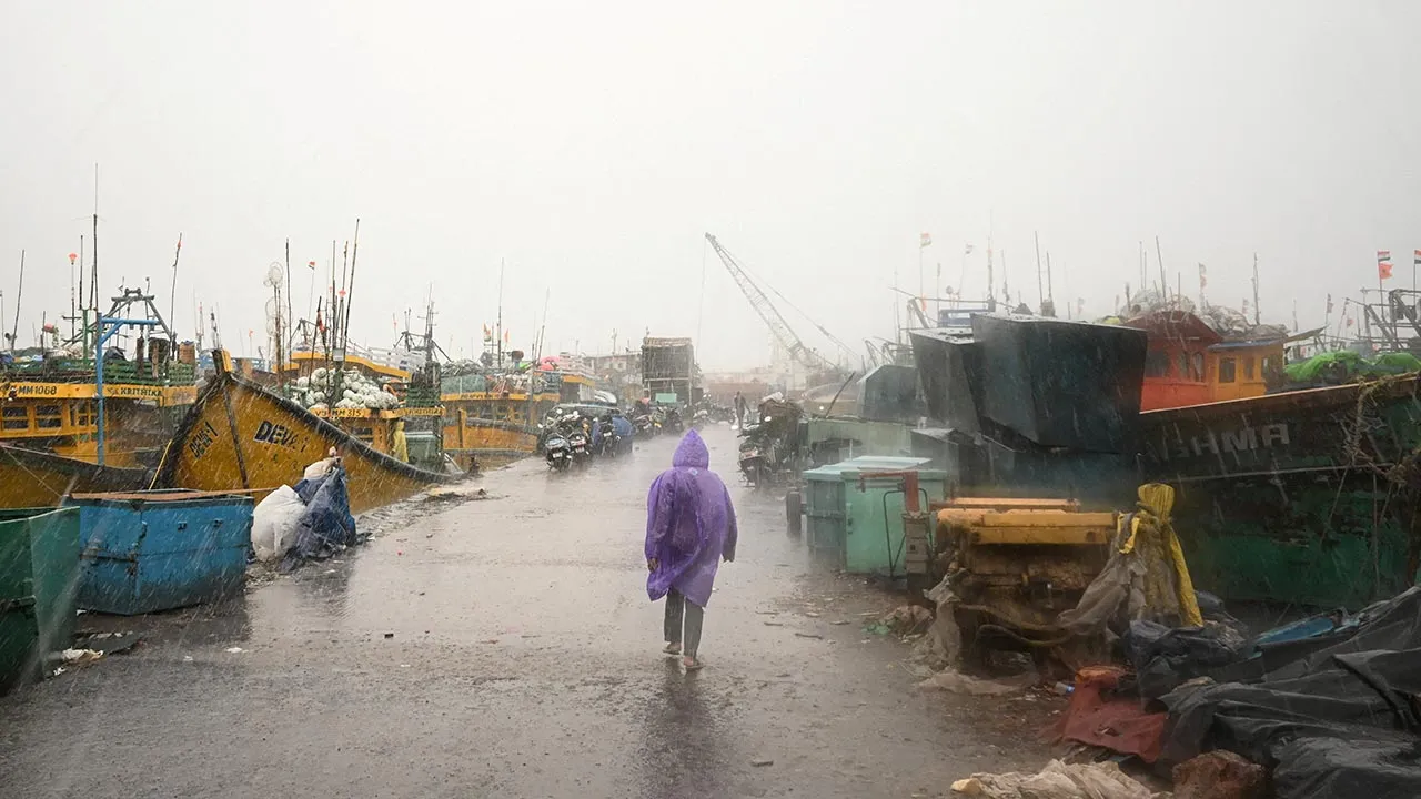 A man walks past docked boats along the harbour amid rain and gusty winds as Cyclone Arnab approaches, in Visakhapatnam, Andhra Pradesh, India, October 27, 2026. REUTERS/Ahamad Shaik TPX IMAGES OF THE DAY