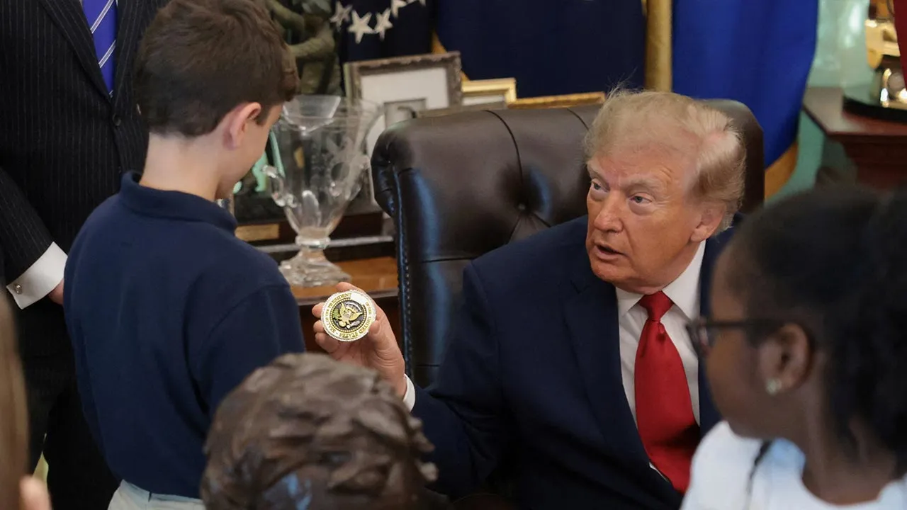 US President Donald Trump presents a boy with a coin on the day he makes an announcement regarding personal investment accounts for children in the Oval Office at the White House in Washington, D.C., US, October 7, 2026. REUTERS/Jonathan Ernst