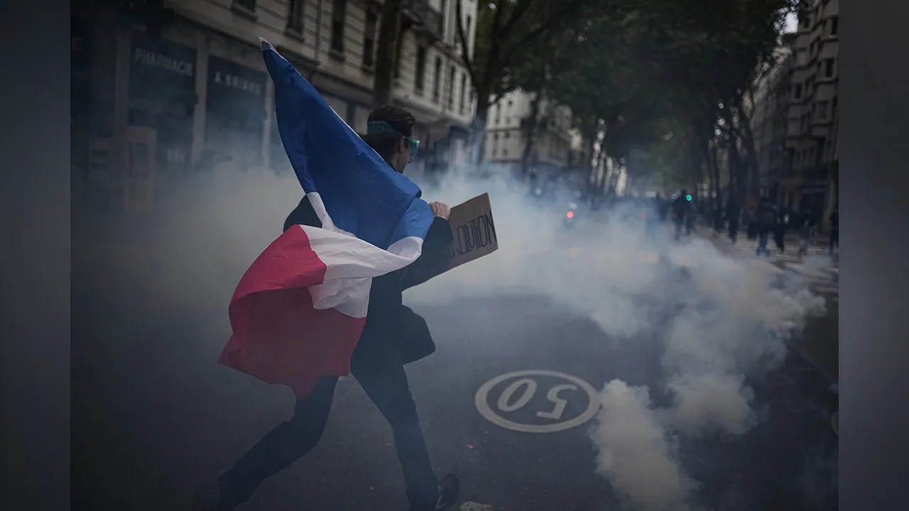 A protester holds a French flag during a demonstration against rising living costs in Lyon, France, Saturday, Oct. 24, 2026. (AP Photo/Laurent Cipriani)