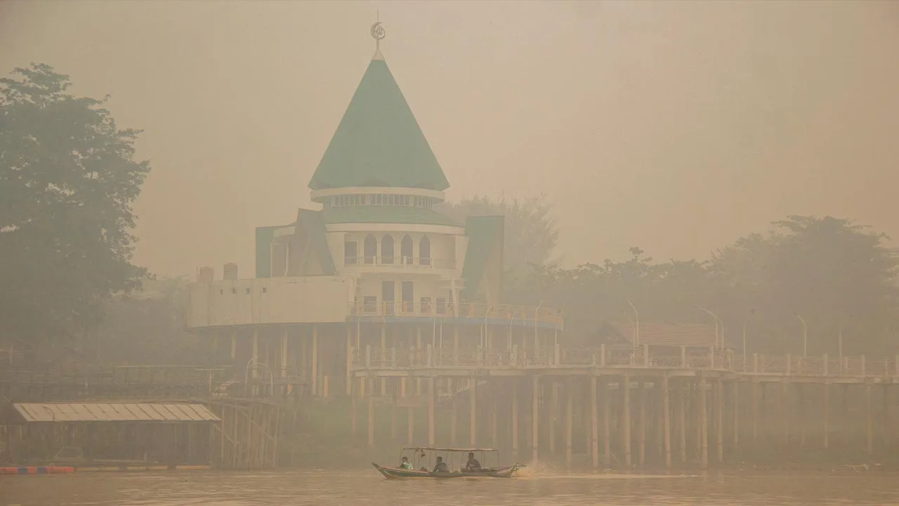 People ride a wooden boat on the Kahayan River as haze from wildfires shrouds Palangka Raya in Central Kalimantan province, Indonesia, October 18, 2026. REUTERS/Arief Rahman Septian Prathama