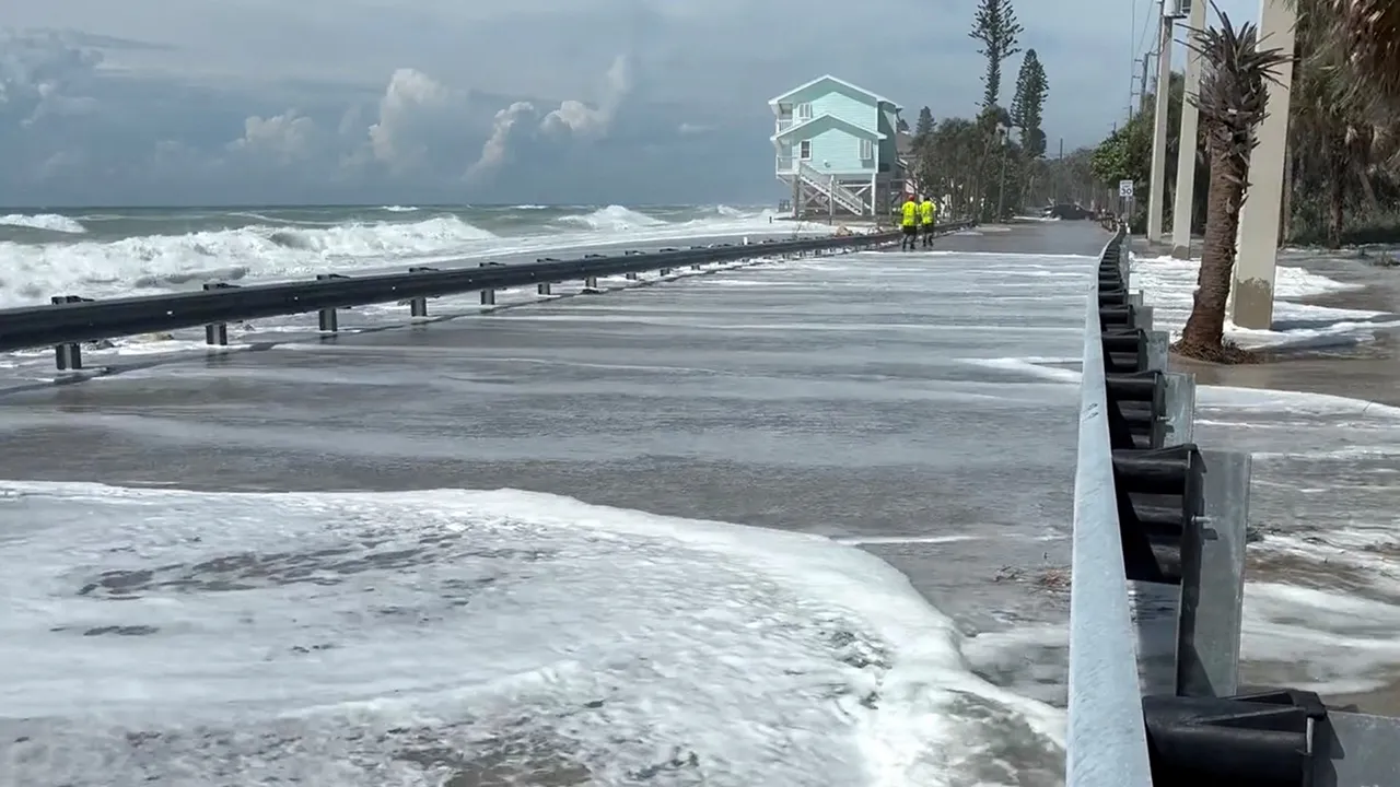 People walk near the shore as waves wash over the road ahead of the arrival of Hurricane Isaias, in Englewood, Florida, US, October 9, 2026. Englewood Area Fire Control District via Facebook/Handout via REUTERS THIS IMAGE HAS BEEN SUPPLIED BY A THIRD PARTY. NO RESALES. NO ARCHIVES. MANDATORY CREDIT. Verification lines : Buildings, electricity poles, road signs, road layout and trees matched file and satellite images in the area. Date verified by government reports of Manasota Key Road in Englewood, Florida