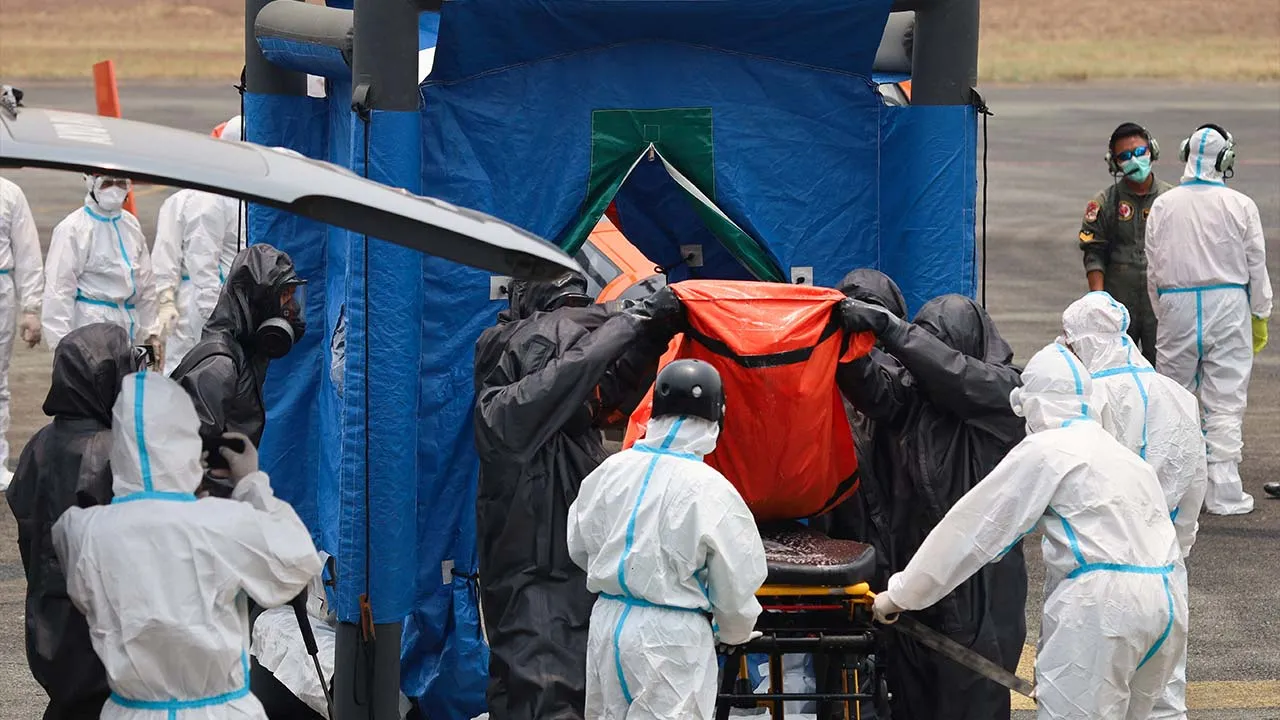 Rescuers in hazmat suits carry a body bag containing a victim recovered from the Virgo Transport 8 ferry, which capsized in the Java Sea while sailing from Surabaya in East Java to Banjarmasin in South Kalimantan, out of a disinfection chamber before the body is transported to a hospital for identification, upon arrival at Sjamsudin Noor airbase in Banjarbaru, South Kalimantan province, Indonesia, October 2, 2026. REUTERS/Abdulrahman Muda Sagala