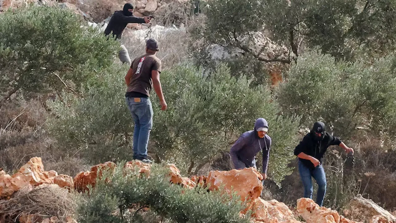 An Israeli settler points a gun amid clashes with Palestinians harvesting olives in Abu Falah near Ramallah in the Israeli-occupied West Bank, October 16, 2026. REUTERS