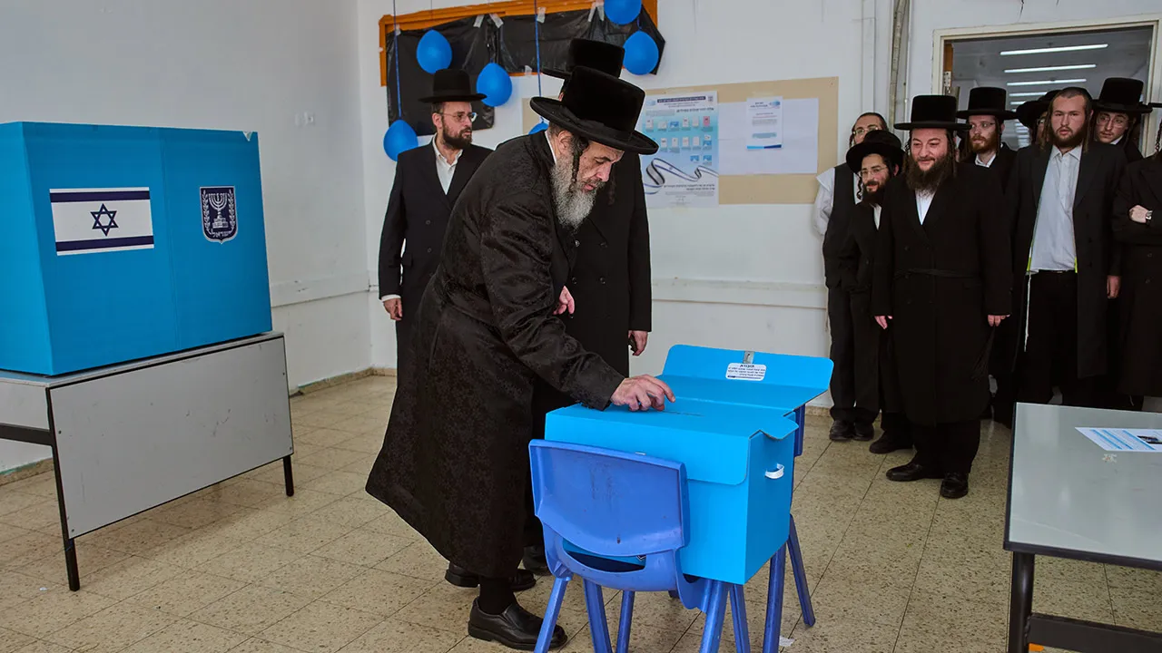Ultra-Orthodox Jewish men watch their Rabbi Chaim Hager casts his ballot at a school serving as a polling station during Israel's general election in Bnei Brak, Israel, Tuesday, Oct. 27, 2026. (AP Photo/Oded Balilty)