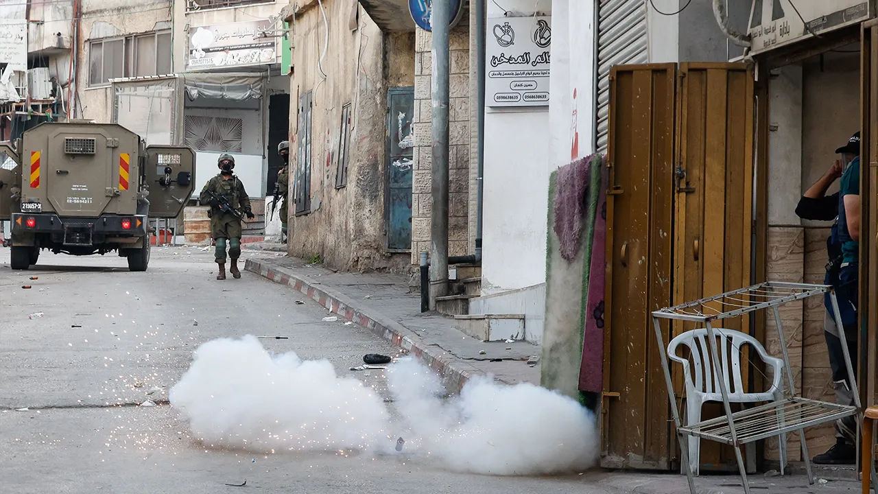Smoke appears after an explosion of a less-lethal explosive device as Israeli soldiers patrol the street during a raid in al-Jalazone near Ramallah, in the Israeli-occupied West Bank, October 14, 2026. REUTERS