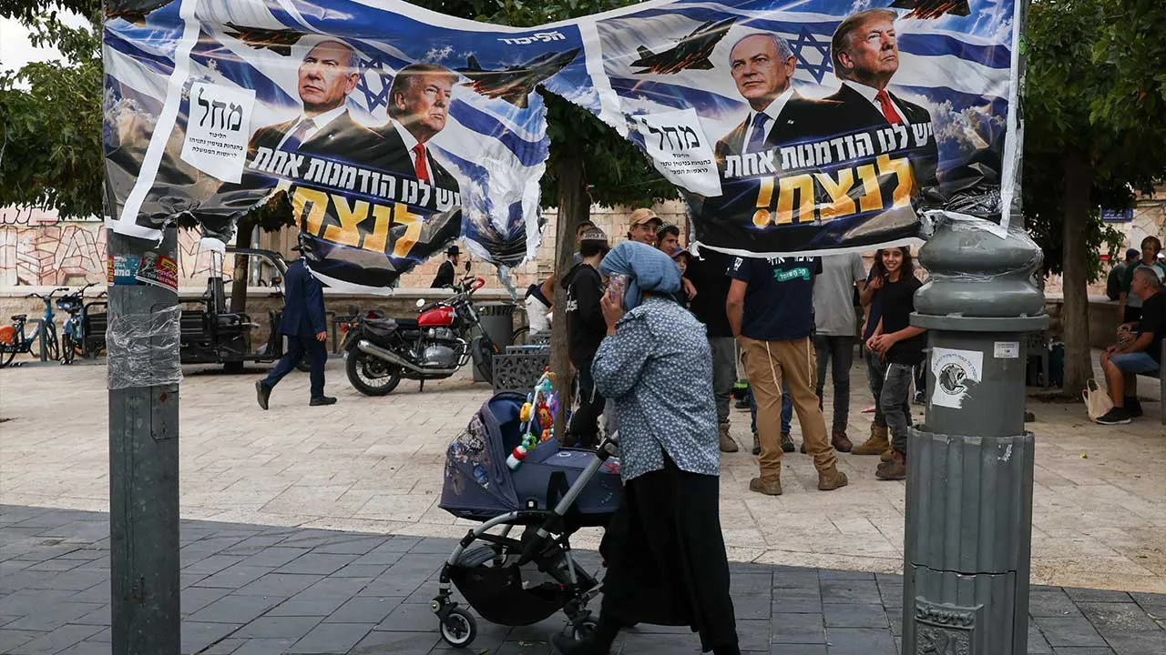 A woman passes by a banner depicting Israeli Prime Minister Benjamin Netanyahu and US President Donald Trump day after the country held a national election, in Jerusalem, October 28 , 2026. REUTERS/Ronen Zvulun