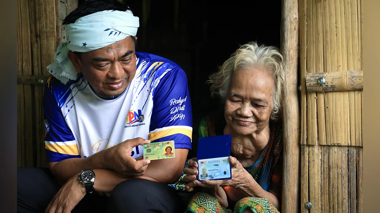 GUA MUSANG, 12 Okt "- Ketua Pengarah Jabatan Pendaftaran Negara (JPN) Datuk Badrul Hisham Alias (kiri) menunjukkan kad pengenalan milik penduduk Orang Asli, Alem Along, ketika melawat kediamannya di Pos Hau, Gua Musang, hari ini.  Lawatan itu sebahagian usaha JPN mendekati masyarakat Orang Asli di pedalaman serta memastikan akses kepada perkhidmatan pendaftaran dan dokumentasi diri. - fotoBERNAMA (2026)