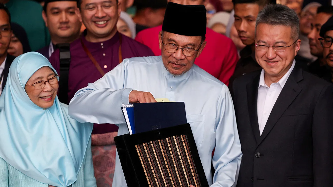 Malaysia's Prime Minister and Finance Minister Anwar Ibrahim holds the 2027 national budget document at the Finance Ministry building as he departs for Parliament to table the budget, in Putrajaya, Malaysia, October 9, 2026. REUTERS/