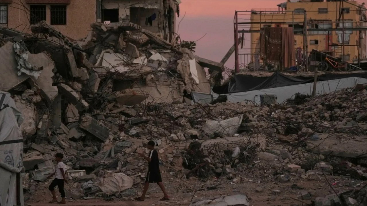 Palestinians walk along a street surrounded by buildings destroyed in Israeli military strikes during the Israel-Hamas war in Gaza City, Tuesday, Oct. 6, 2026. (AP Photo/Jehad Alshrafi)