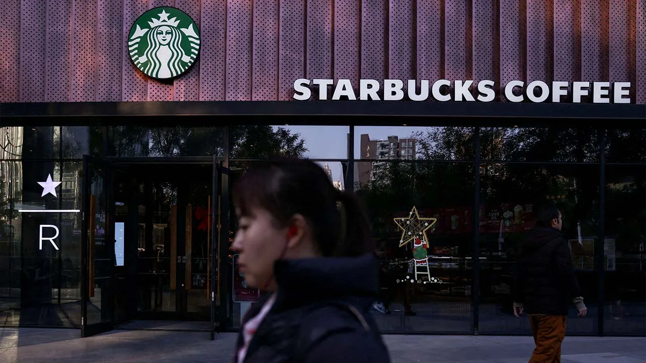 FILE PHOTO: People walk past a Starbucks coffee shop in Beijing, China, November 4, 2025. REUTERS/Tingshu Wang/File Photo
