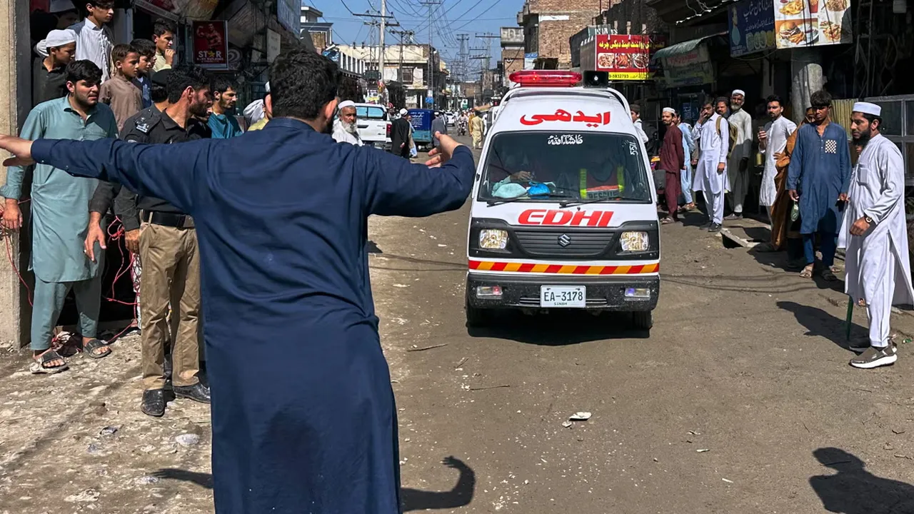 A volunteer clears the way for an ambulance transporting injured school children following a roof collapse at a private school in Peshawar, Pakistan, Thursday, Oct. 15, 2026. (AP Photo/Maaz Awan)