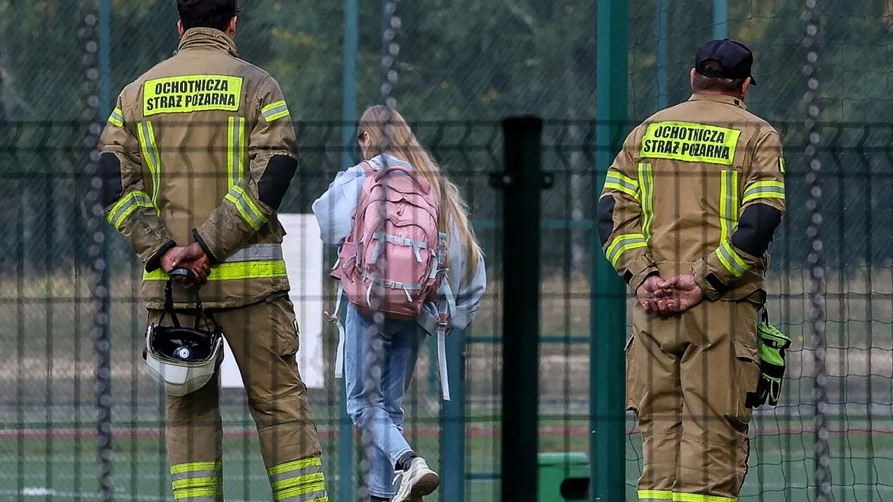 A child walks next to fire fighters working at the site of a deadly attack at a school by a 15-year-old former pupil, in Leszczydol-Nowiny, Wyszkow County, northeast of Warsaw, Poland, October 8, 2026. The Thursday incident came a day after another attack at a different Polish school. REUTERS/Kacper Pempel