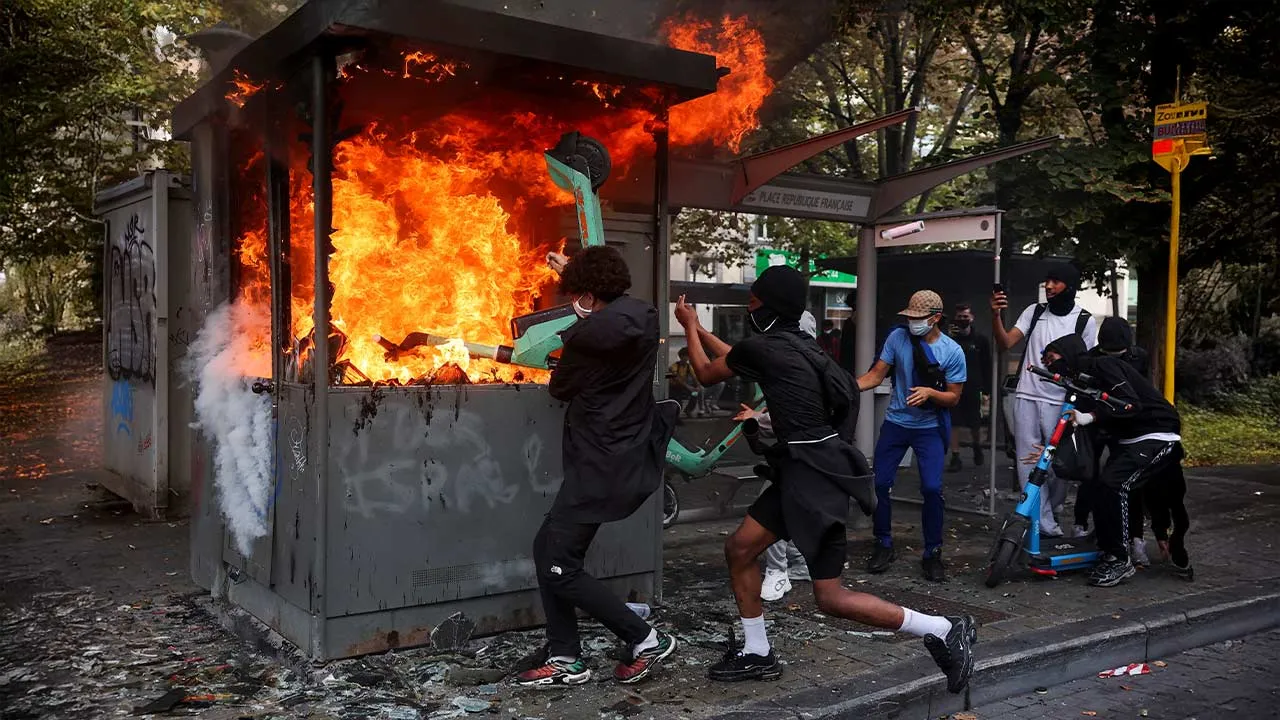 People attempt to put an electric scooter into a burning structure on a street, on the day of a spontaneous street protest of high school students against education reforms introduced by the Wallonia-Brussels Federation government and an increase in student fees, in Liege, Belgium, October 7, 2026. REUTERS/Stephanie Lecocq